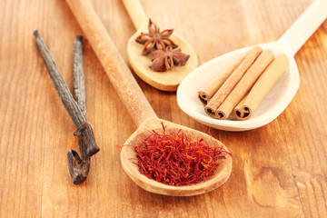 Fragrant spices in wooden spoons on a wooden background
