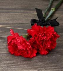 Washable wall murals Red, black, white carnations and black ribbon on grey wooden background