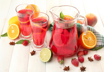 sangria in jar and glasses with fruits, on white wooden table