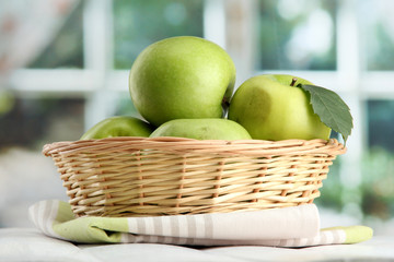 Ripe green apples with leaves in basket,