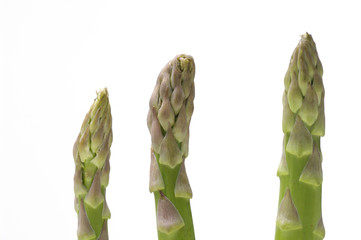 three asparagus spears standing over white