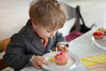 Little toddler blowing two birthday candles