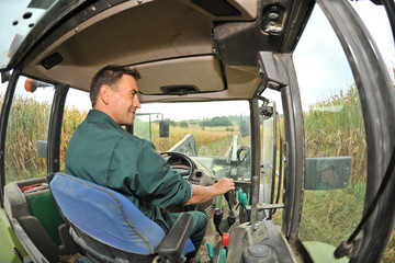 Obraz premium Farmer driving tractor in corn field