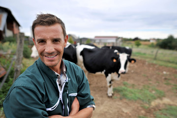 Smiling cow breeder standing in in front of cow herd