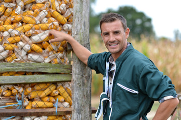 Cheerful farmer standing by corn silo © goodluz
