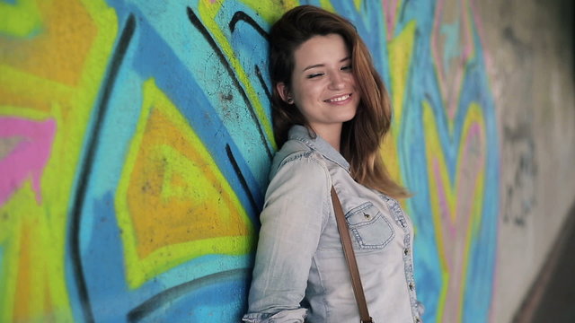 Portrait of smiling beautiful woman standing in front of graffit