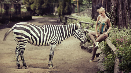 Beautiful lady sitting next to a zebra © konradbak