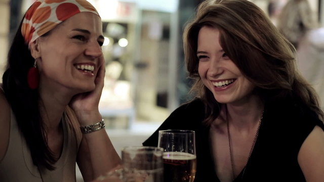 Female friends in restaurant drinking beer in the evening, stead