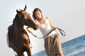 young happy woman with horse on sea background