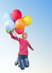 Girl jumping outside with balloons