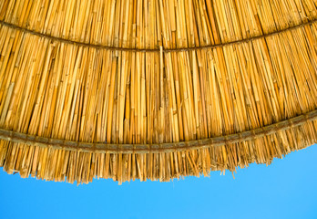 Beach straw parasol umbrella against the blue sky