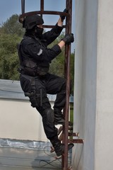 special forces officer climbs a ladder to the chimney,