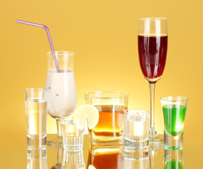 a variety of alcoholic drinks on yellow background