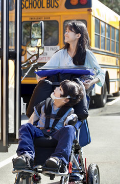 Big sister pushing disabled brother in wheelchair at school