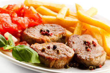 Grilled steaks, French fries and vegetables