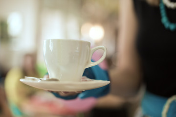 In a hand a cup of coffee