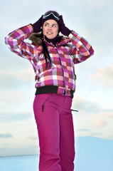 Beautiful young woman wearing skiing suit posing outdoors in win