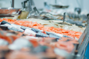 Fresh fishes lie on table with ice in supermarket