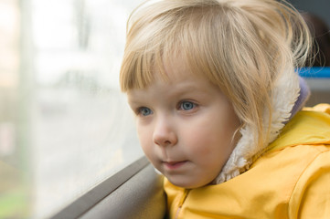 Adorable girl in yellow jacket ride on bus. Look to window