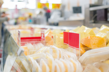 Variety of cheese pieces and information labels in supermarket