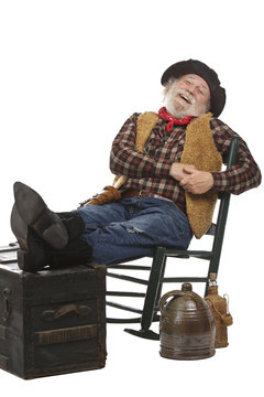 Happy old cowboy sits in rocking chair with feet up