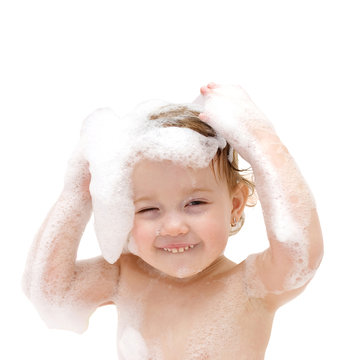 baby girl with soap suds on hair taking bath.