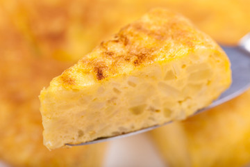 Portion of Spanish omelette with a tortilla as background