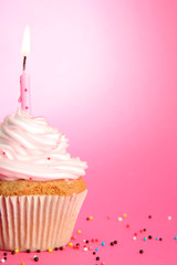 tasty birthday cupcake with candle, on pink background