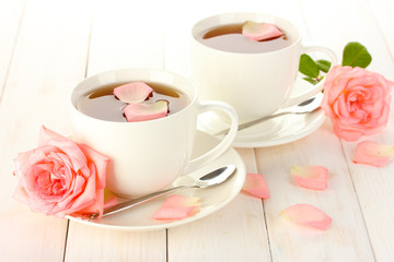 cups of tea with roses on white wooden table