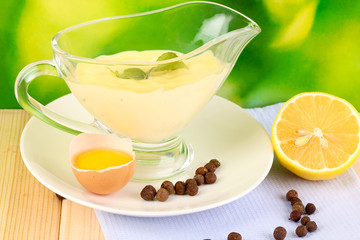 Mayonnaise in bowl on wooden table on nature background