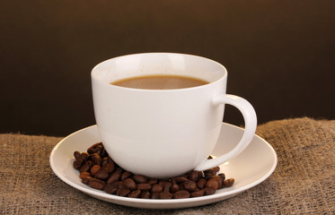 Cup of coffee on sacking on brown background
