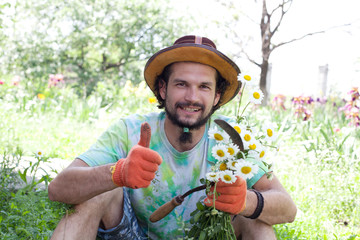 Man holding the camomile bouquet and the sickle