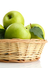 Ripe green apples with leaves in basket isolated on white