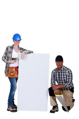 A team of tradespeople standing around a blank sign