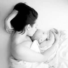Black and white mother and baby sleeping in bed.