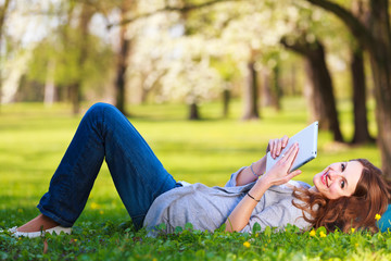 Young woman using her tablet computer while relaxing outdoors