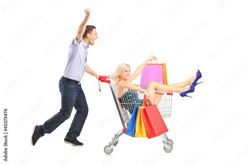 Wall mural excited person pushing a shopping cart, happy woman with bags in