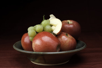 Bowl of whole and sliced fruit.