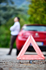 Red warning triangle with a broken down car