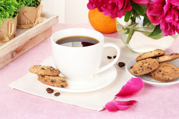 cup of coffee, cookies, orange and flowers on table in cafe