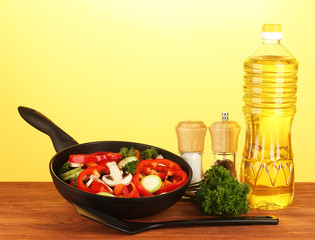 frying pan with vegetables on yellow background