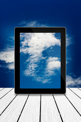 Tablet computer on wood,cloudy sky computing technology concept