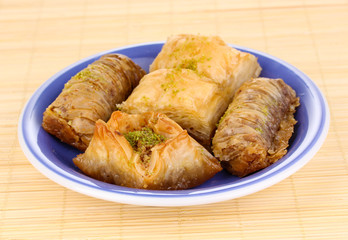 Sweet baklava on plate on bamboo mat