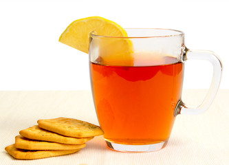 Glass cup of tea with lemon and crackers