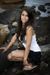 Young woman on rocks in front of the sea