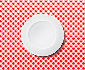 Empty plate on a red checked tablecloth