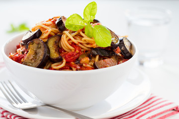 Spaghetti with eggplants and tomatoes served on a white plate