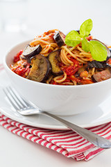 Spaghetti with eggplants and tomatoes served on a white plate
