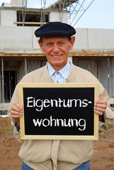 Rentner mit Schild Eigentumswohnung