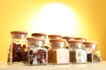 powder spices in glass jars on yellow background